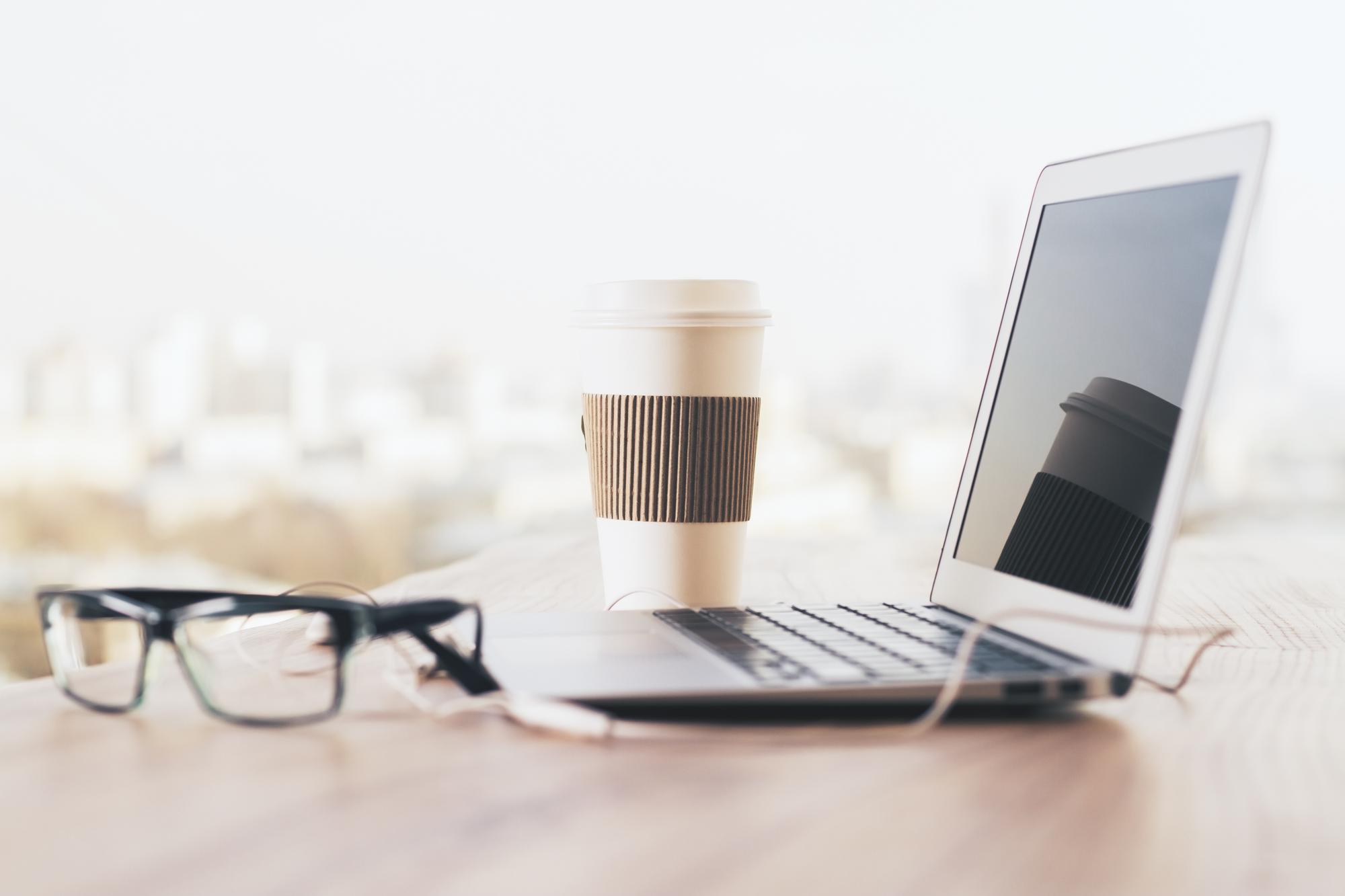 Kaffee und Laptop auf Holztisch - Arbeitsatmosphäre